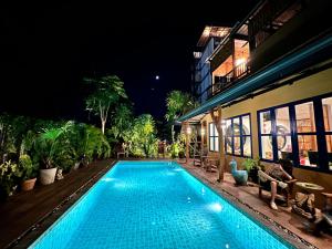 奈扬海滩绿纳 旅舍的一座游泳池,在晚上在建筑物前