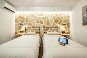 古维亚Mathraki Resort的带石墙的客房内的三张床