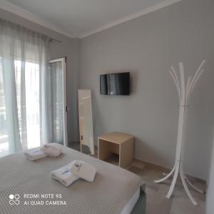 阿莫利亚尼岛纳法斯卡公寓的白色卧室设有一张床和墙上的电视