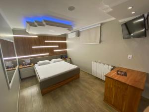 卡拉济纽Motel Casa de Pedra的一间卧室配有一张床、一张书桌和一台电视。