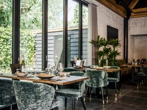 Sint-OedenrodeLindenhuys Logies的餐厅设有绿色的椅子和桌子以及窗户。