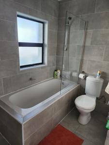 哈博罗内Sarona Studio A103的带浴缸、卫生间和窗户的浴室