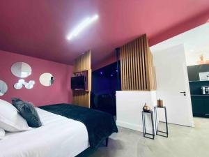 波尔多La Litchi Le 50 Suites and Spa centre ville的卧室配有一张带粉红色墙壁的大床