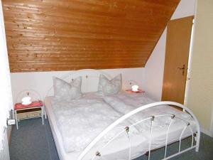 RambinRuegen_Fewo 23的卧室配有白色床和木制天花板