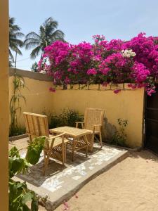 圣路易斯Le Poulagou的庭院配有两把椅子和一张桌子,庭院里种着粉红色的鲜花