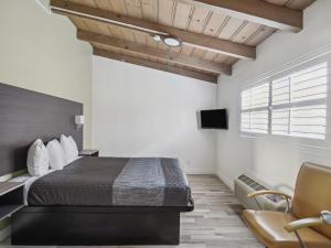 滨海城蒙特利湾愉景酒店的一间卧室配有一张床、一把椅子和电视。