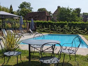 科隆热Château de Vassinhac chambres d'hôtes Collonges la rouge的游泳池旁的桌椅