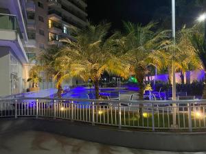 里约热内卢Suíte & Flat Premium Rio Stay - Rio Centro的棕榈树和夜间游泳池的度假村