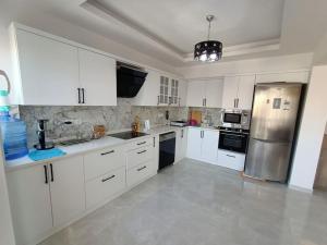 库萨达斯Flat For Rent At The City Center Of Kuşadası的厨房配有白色橱柜和不锈钢冰箱