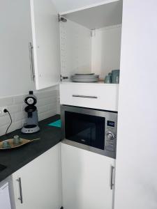 Le Mesnil-Saint-DenisSPA JUNGLE的厨房配有白色橱柜和微波炉