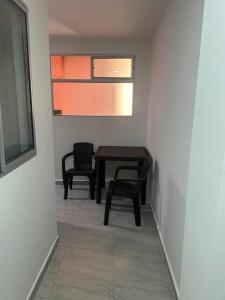 麦德林Lindo apartamento Medellín zona céntrica的客房设有桌子、两把椅子和窗户。