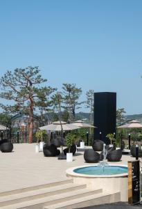 群山市Gunsan Stay Tourist Hotel的庭院里的喷泉,配有椅子和遮阳伞