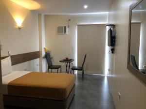 宿务18 Suites Cebu的酒店客房带一张床、一张桌子和椅子
