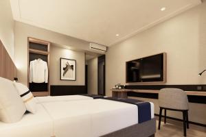DawuhanFieris Hotel & Convention Kertajati的一间酒店客房,配有白色的床和电视