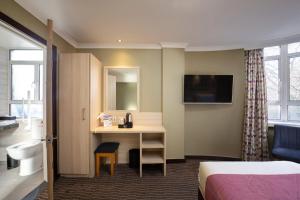 伦敦President Hotel的配有一张床和一张书桌的酒店客房