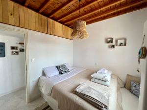 圣斯特凡诺斯Lux Mykonos house的一间卧室配有白色床单和木制天花板。