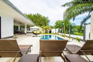 奥南海滩RUSARDI Poolvilla Ao Nang - new Villa 4 Bedrooms 4 Bathrooms, 10m Pool的一个带椅子的户外庭院和一个游泳池