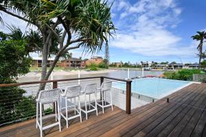 穆卢拉巴Stunning Mooloolaba Waterfront Home -10 guests ZB1的一个带两把椅子的甲板和一个游泳池