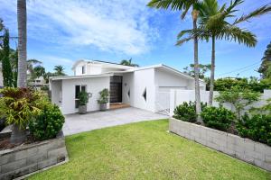 穆卢拉巴Stunning Mooloolaba Waterfront Home -10 guests ZB1的棕榈树和草地的白色房子