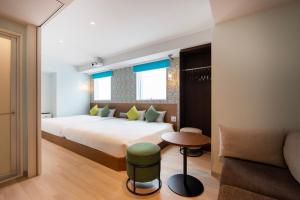 东京karaksa hotel colors Tokyo Yaesu的一间卧室配有一张大床和一张沙发