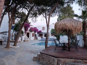 纳克索斯岛卡斯特拉基Naxos Summerland resort的庭院配有椅子和一张带草伞的桌子。