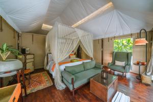 德格拉朗Kanva Ubud的一间卧室配有一张床、一张沙发和一把椅子