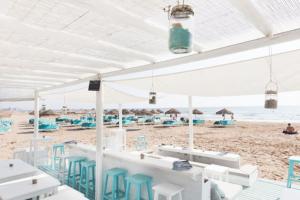 瓦伦西亚Valencia Ático playa Patacona. Parking incluido的海滩上设有白色的桌子和蓝色的椅子,还有大海