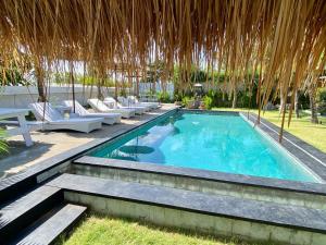 乌鲁瓦图Bella Bali的一个带椅子和草伞的游泳池