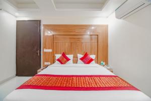 新德里Hotel Classic Paradise Inn的一间卧室配有一张带红色枕头的大床