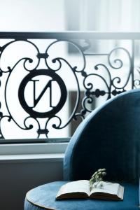 枫丹白露Hôtel & SPA Napoléon的一本书,放在带窗户的蓝色椅子上