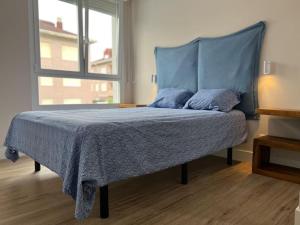 擞莫Acogedor apartamento en Somo的一张带蓝色毯子和窗户的床