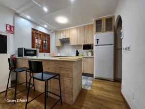 卡塔赫纳VILLA ARTEP Lujoso apartamento con piscina comunitaria的厨房配有白色冰箱和2个吧台凳