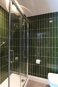 萨克斯曼德姆The Bell Hotel, Saxmundham的绿色瓷砖浴室设有淋浴和卫生间
