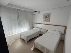贝尼塔切利Apartamentos Flamingo Hills的配有2张床的白色墙壁和窗户客房