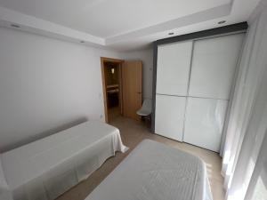 贝尼塔切利Apartamentos Flamingo Hills的白色卧室设有床和滑动玻璃门