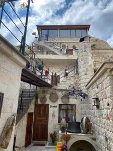 于尔居普Bayar Cave Suites的一座带楼梯和阳台的石头建筑