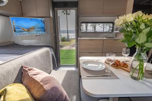 恩格夫Dream Caravan's - קרוואנים מושלמים למשפחות בחוף כורסי בכינרת的一个带桌子和墙上电视的大篷车