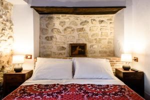 SantʼIonaLaVistaDeiSogni La Perla的一间卧室设有石墙、一张床和两盏灯。