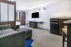 奥斯汀麦克罗迪尔温德姆韦汉姆奥斯丁机场酒店的酒店客房设有一张沙发和一张带电视的书桌。