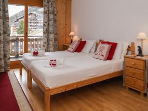 南达Apartment Les Etagnes 2est by Interhome的一间卧室配有一张大床,配有白色床单和红色枕头