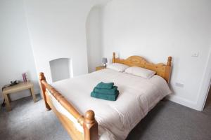 贝尔法斯特House in the Gaeltacht Quarter的一间卧室配有一张木床,上面有绿毛巾