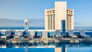檀香山Pacific Monarch Hotel的一座带椅子的游泳池以及一座建筑