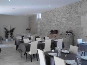 Bernières-sur-Mer吕泽尔恩宾馆的一间设有桌椅的用餐室和砖墙