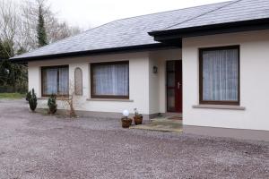 基拉尼Killarney , Ring of Kerry 2 Bed Apartment 2 Bathrooms的白色的房子,设有两扇窗户和车道