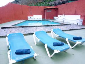 Las CrucesLive Garachico Villa Daute con terraza y piscina的两张蓝色躺椅和一个游泳池