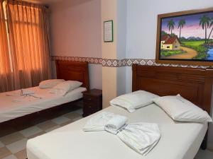 图卢阿Hotel Los Corales Tulua的墙上画画的房间里设有两张床