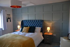 马斯顿The Thorold的一间卧室配有一张带蓝色床头板的床和两盏灯。