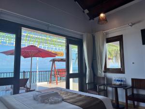 富国The Poplar Resort Phú Quốc的一间卧室配有一张床,阳台配有遮阳伞