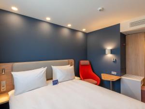 埃格斯托夫Holiday Inn Express - Hamburg South A7-AS42, an IHG Hotel的一间卧室配有一张床和一张红色椅子