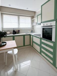 戛纳Cosy stay - LA CROISETTE的厨房配有绿色和白色的橱柜和桌子